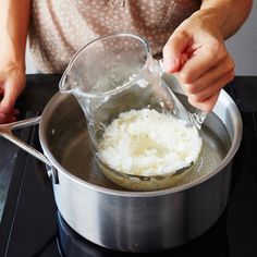 a woman is mixing rice in a pot on the stove