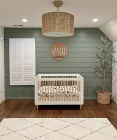 a baby's room with green walls and white furniture