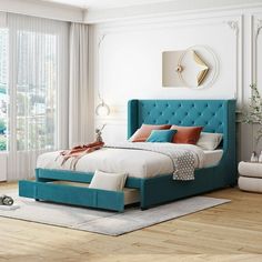 a bedroom with white walls and wood flooring has a blue upholstered bed