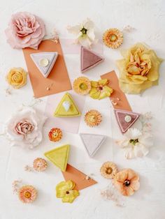 several different types of flowers are arranged on a white surface with pink and yellow accents