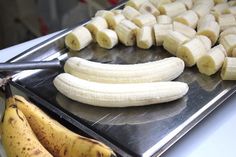 some bananas are sitting on a metal tray and ready to be cut into smaller pieces