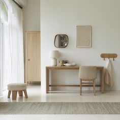 a white room with a table, chair and mirror on the wall next to it