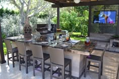 an outdoor kitchen with bar seating and television