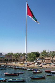 several boats in the water near a flag pole