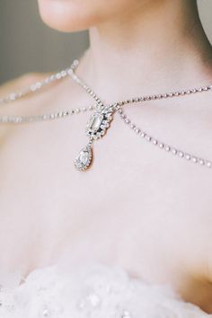 a close up of a woman's neck wearing a necklace with pearls on it