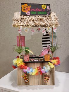 an ice cream stand decorated with flowers and tiki hut decorations for a tropical themed birthday party