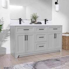 a bathroom vanity with two sinks and mirrors on it's sides, in front of a plant