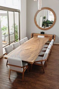 a large wooden table sitting in the middle of a room with white chairs around it