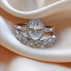 a close up view of a diamond ring on a white satin surface with the fabric in the background