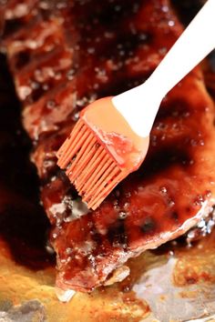 a spatula being used to brush barbecue ribs with bbq sauce