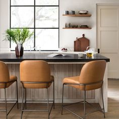 three chairs are sitting in front of a kitchen island with a potted plant on it