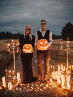 two people standing next to each other in front of candles and jack - o'- lanterns