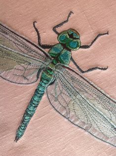 a green dragonfly sitting on top of a pink cloth