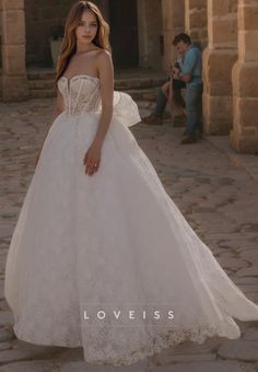 a woman in a white wedding dress standing on a stone floor with her hands behind her back