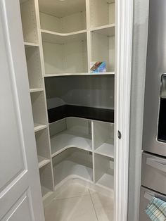 an empty pantry with white shelves and black counter tops