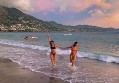 two women in bikinis running into the ocean