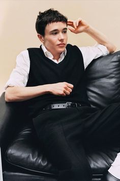 a young man sitting on top of a black leather chair