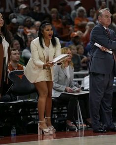 a woman in a white dress is on the sidelines with an official looking at her