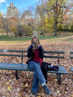 a woman is sitting on a park bench reading a book