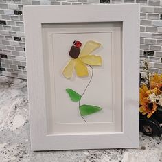 a white frame with a yellow flower and a ladybug on it