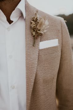 a man in a suit with a boutonniere and flower pinned to his lapel