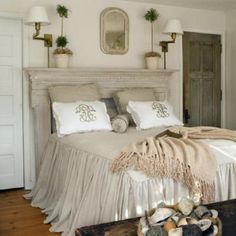 a bed with white linens and pillows in a bedroom next to a wooden table