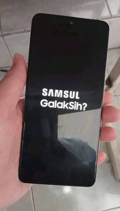 someone holding up a cell phone with the text samsung galaksin? on it