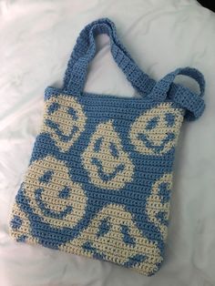 a crocheted blue and white purse sitting on top of a bed next to a pillow