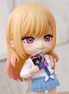 a close up of a toy doll with pink eyes and blonde hair holding a book