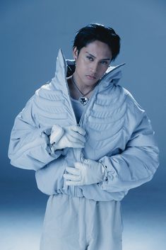 a male in a blue jacket and white gloves is posing for a photo with his hands on his chest