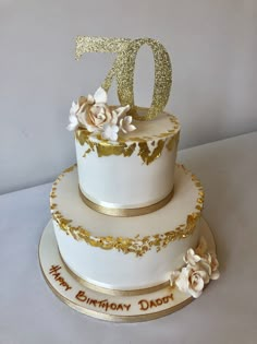 a white and gold birthday cake with flowers on top