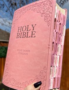 a person holding a pink bible in their hand