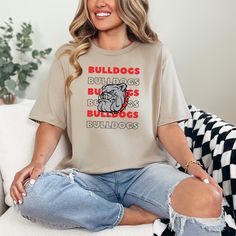 a woman sitting on a couch wearing a t - shirt that says bulldogs, buildings and bulldogs