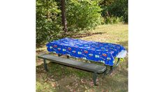 a blue picnic table cover sitting on top of a metal bench in front of trees