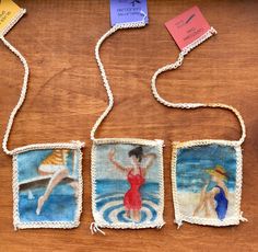 three pictures are hanging from string on a wooden table with tags attached to the strings