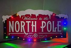 the north pole sign is lit up with christmas lights and snowflakes on it