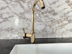 a white sink sitting under a faucet next to a marble counter top in a kitchen