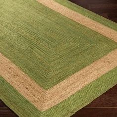 a green and beige area rug on top of a wooden floor