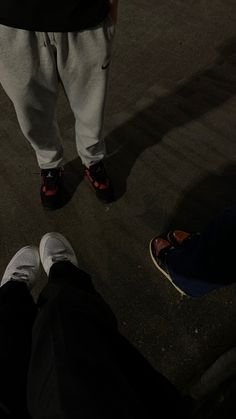 two people standing next to each other with shoes on and one person wearing white pants