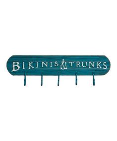 a wooden sign with the words bikinis and trunks written in white on blue wood