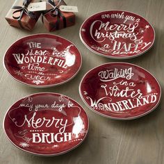 four red plates with white lettering on them and presents in the back ground next to it