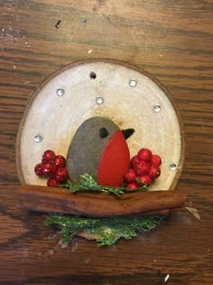 a small bird sitting on top of a wooden table next to some red berries and greenery