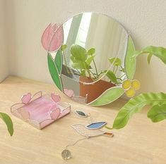 a mirror sitting on top of a wooden table next to a potted plant and other items