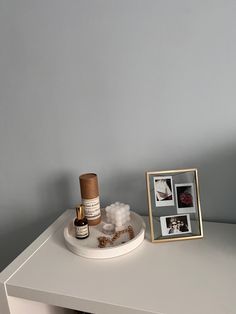 a white table topped with an empty tray filled with bottles and other items next to a framed photograph