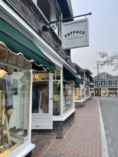 a store front with clothes on display in the window and outside windows that are decorated with green awnings