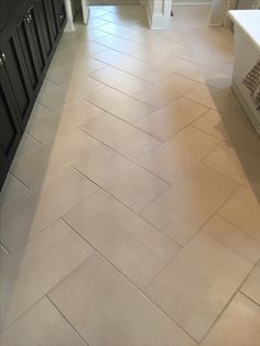 a large kitchen with black cabinets and white counter tops, along with tile flooring