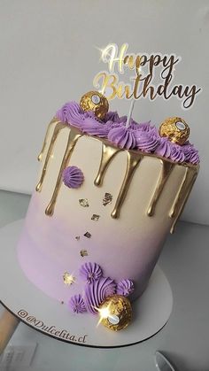 a birthday cake with purple frosting and gold decorations