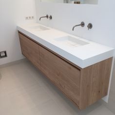 a bathroom with two sinks and mirrors on the wall next to toilet paper dispenser