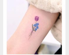 a small flower tattoo on the right arm and leg, with blue flowers in it