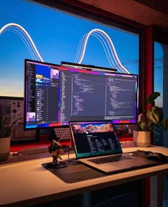 a laptop computer sitting on top of a desk next to a large monitor and keyboard